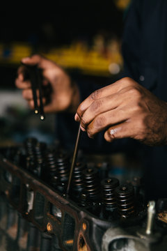 Mechanic fixing an engine for a head gasket repair in a garage.