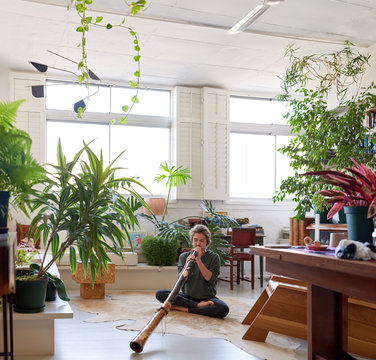 Woman playing the didgeridoo at home