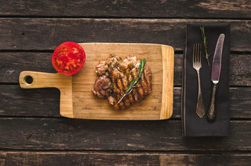 Grilled turkey meat and red tomato on the wooden background.