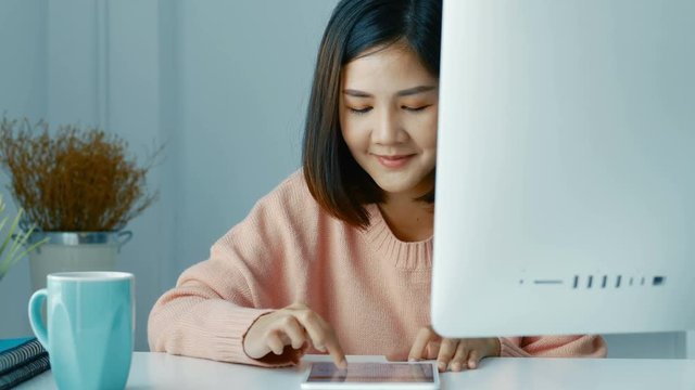 Young asian women business owners using app smartphone and play the stock maket in office.