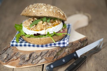 creamy-soft cheese made of cow's milk, authentic french cheese on black slate plate with honey, walnuts