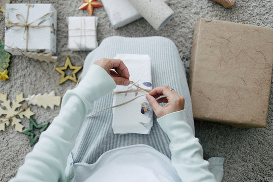 Woman wrapping Christmas present with handmade natural gift paper