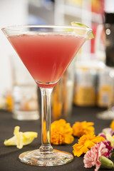 A lovely refreshing summer cocktail with carnations as decoration and a lime garnish in a martini glass.
