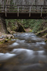 Fototapeta na wymiar Water Flows Under Wooden Bridge