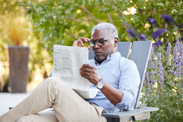 Portrait of African American Senior man reading the newspaper on his patio outside
