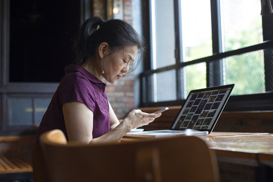 One senior asian woman working with laptop in cafe