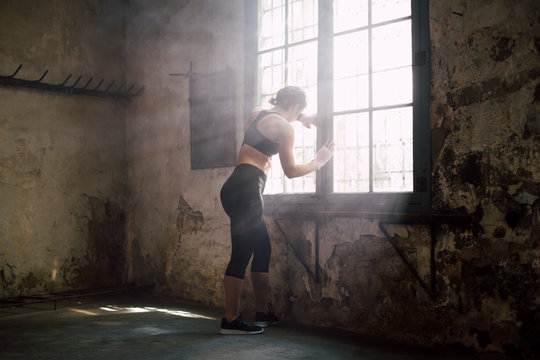 Young strong brunette woman resting after boxing workout.