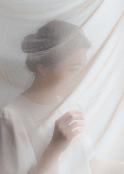 Portrait of girl standing behind silk scarf