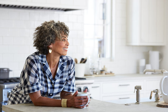 Senior African American woman in her kitchen drinking coffee