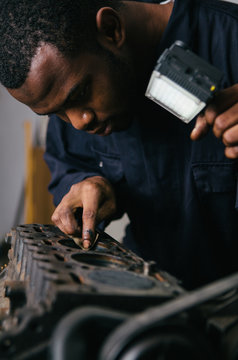 Mechanic fixing an engine for a head gasket repair in a garage.