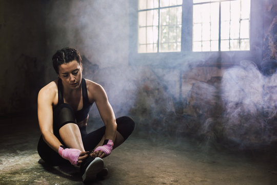 Strong brunette woman resting after boxing workout.