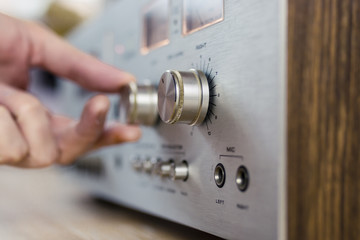 Fototapeta na wymiar Hand Turning a Dial on a Vintage Home Stereo Equipment