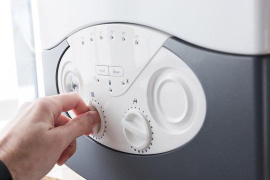 Hand Turning a Knob on Washing Machine Dashboard