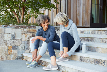 Senior women friends relaxing and talking before a run together sitting on steps