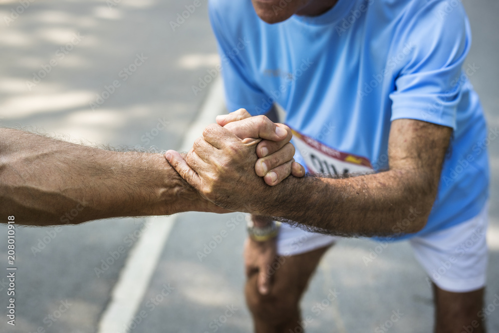 Wall mural senior runner giving a helping hand