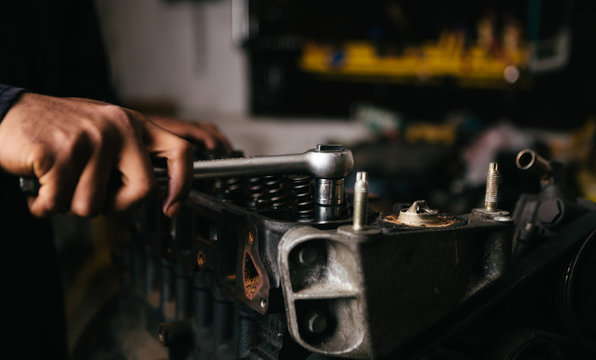 Mechanic fixing an engine for a head gasket repair in a garage.