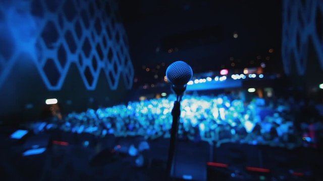 Pan shot of microphone on stage before a concert with audience in front
