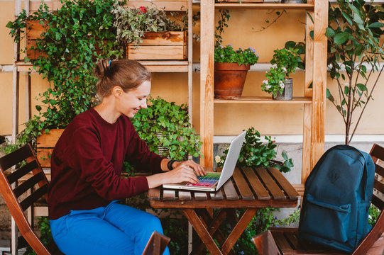 Young woman working on laptop in outdoors cafe