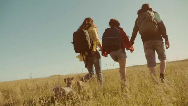 happy family slow motion video walking on nature boy girl and mom in a field on trekking trip. tourists with backpacks traveling. happy family lifestyle travel tourism concept