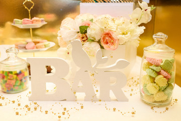 Holiday candy bar in white color, copy space. Stylish luxury decorated wedding reception, dessert table. Catering in restaurant. Table with cakes, sweets and flowers