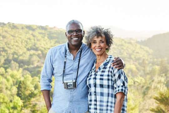Portrait of African American Senior couple with a vintage film camera laughing outdoors