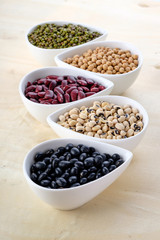 Assortment beans in white ceramic bowl, focus on the Mung Beans. Black, soybean, red kidney , black eye peas and mung beans.