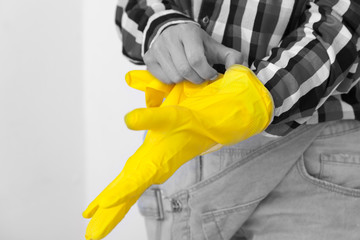 Сlose up of young woman  in jeans and plaid shirt hands wearing protective rubber yellow gloves. Women's housework and safety, housekeeping concept