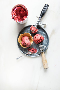 Raspberry ice cream in different spoons  being served in a wafer glass