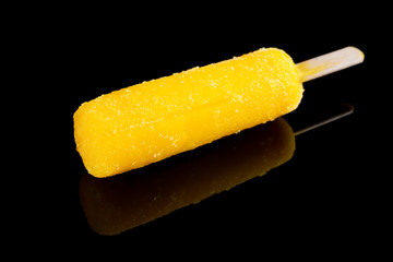 yellow popsicle on a black background with reflection