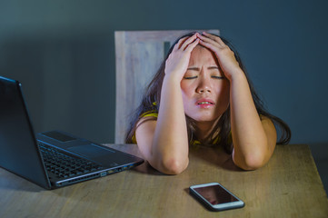 dramatic portrait scared and stressed Asian Korean teen girl or young woman with laptop computer...