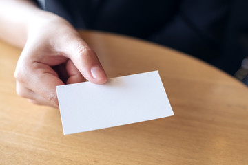 Obraz premium Businesswoman gospodarstwa i podając pustą wizytówkę komuś na stole w biurze