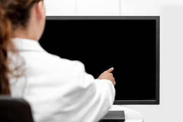 Rückenansicht Ärztin oder Laborantin zeigt auf den Monitor mit Textfreiraum