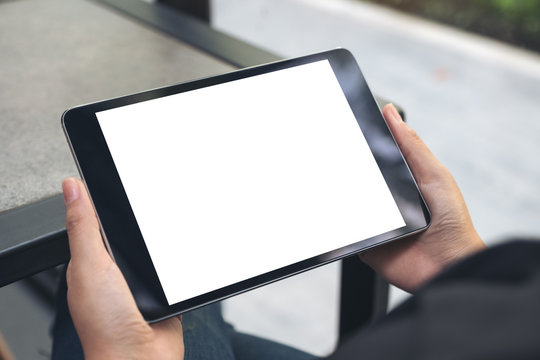 Mockup image of hands holding black tablet pc with blank white desktop screen
