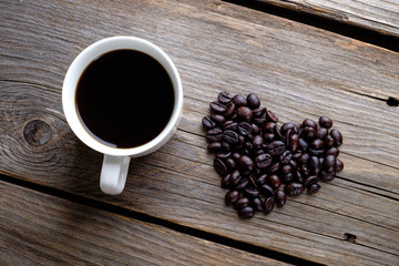 Coffee and heart roasted coffee beans on rustic wooden table