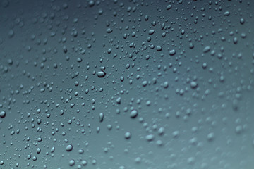 water drops on gray window glass on rainy day, blurred raindrop for abstract fresh air background