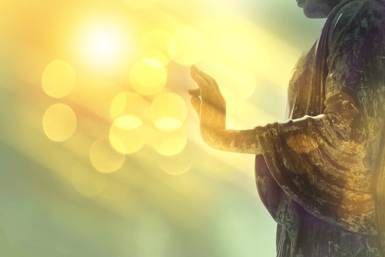 hand of buddha statue with yellow bokeh background, light of wisdom and concentration concept