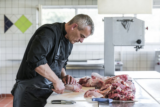 Man working as butcher cutting small pieces of meat - Powered by Adobe