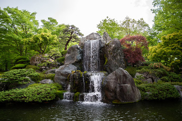 Fototapeta na wymiar cascade flowing over mossy boulders in a garden.