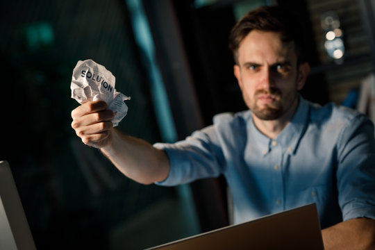 Young man showing crumpled paper and looking furiously at camera failed to reach solution in business