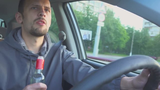 Drunk Driver. Close up shot of Man drinks vodka while in the car. Danger on the road.