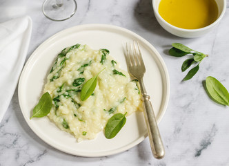 Gentle cream risotto with spinach, served with wine. Light background.