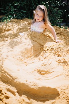 Adorable girl posing with sand mermaid tail in sunny summer day