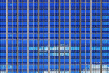 multi storey glass cladding facade office building. translucent exterior metal aluminum frame reflecting sky and lighted room inside. business work place tower.