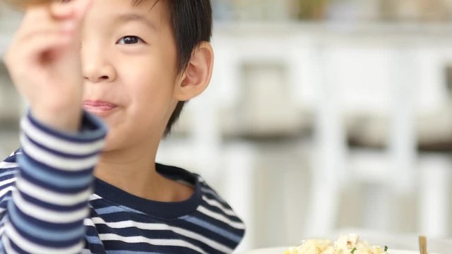 Cute Asian child eating breakfast in a restaurant 