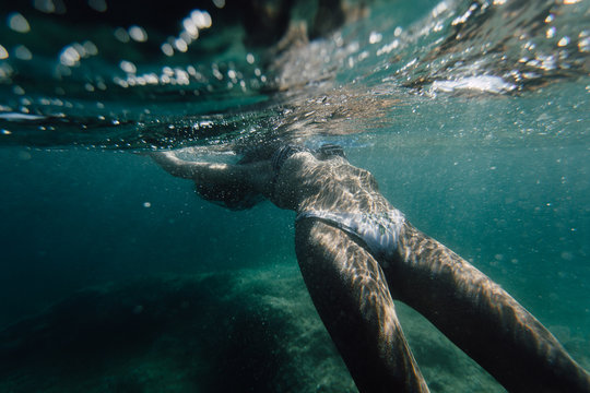 Wide shot of a woman swimming underwater