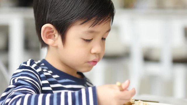 Cute Asian child eating breakfast in a restaurant 