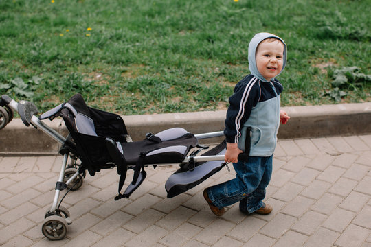 Cute boy carrying his stroller