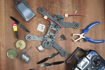 assembly of a quadrocopter assembly of parts on a wooden table using various tools