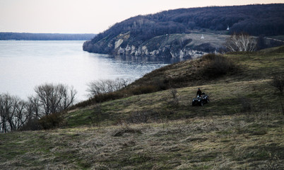 Samara Russia CIRCA April 2018 a man riding ATV in hunting park with river and hills