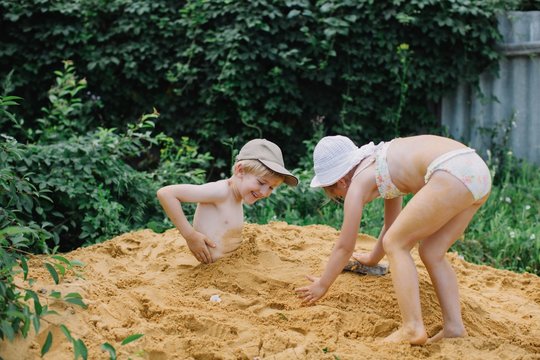 Lovely girl and boy playing with sand